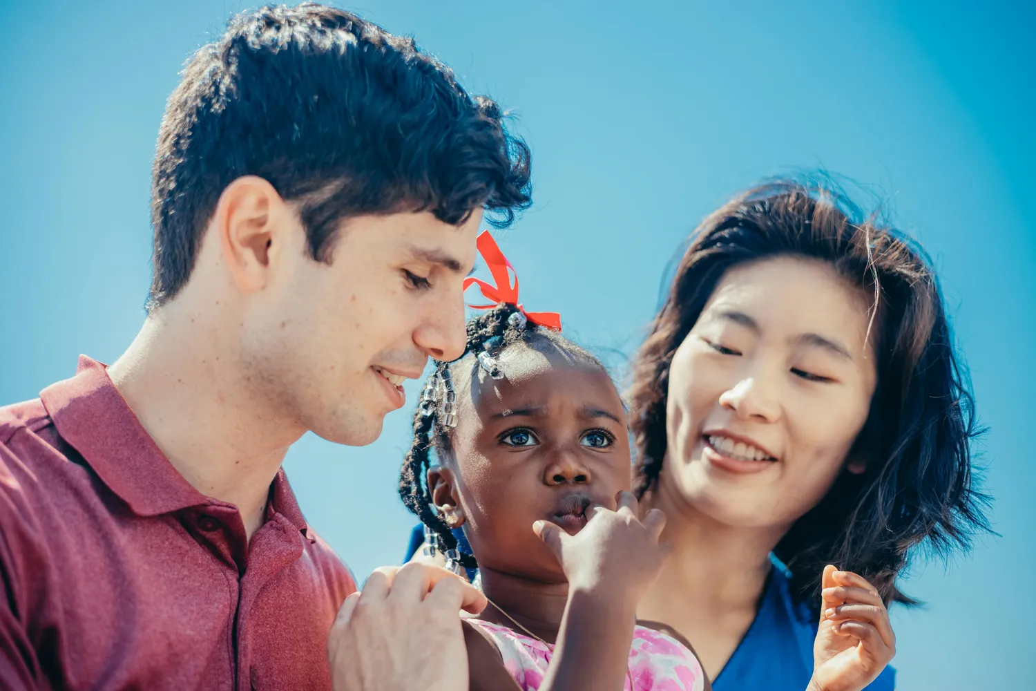 Versicherungsvermittlung Keskin – Dieses Bild zeigt eine vielfältige Familie, die draußen unter blauem Himmel zusammenkommt.