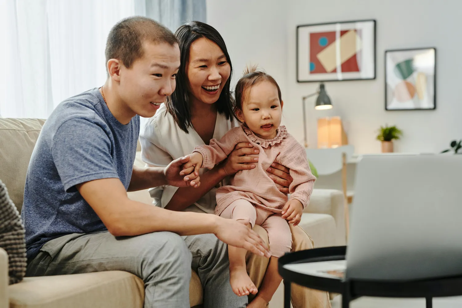 Versicherungsvermittlung Keskin - Glückliche Familie liegt auf der Couch und benutzt Laptop